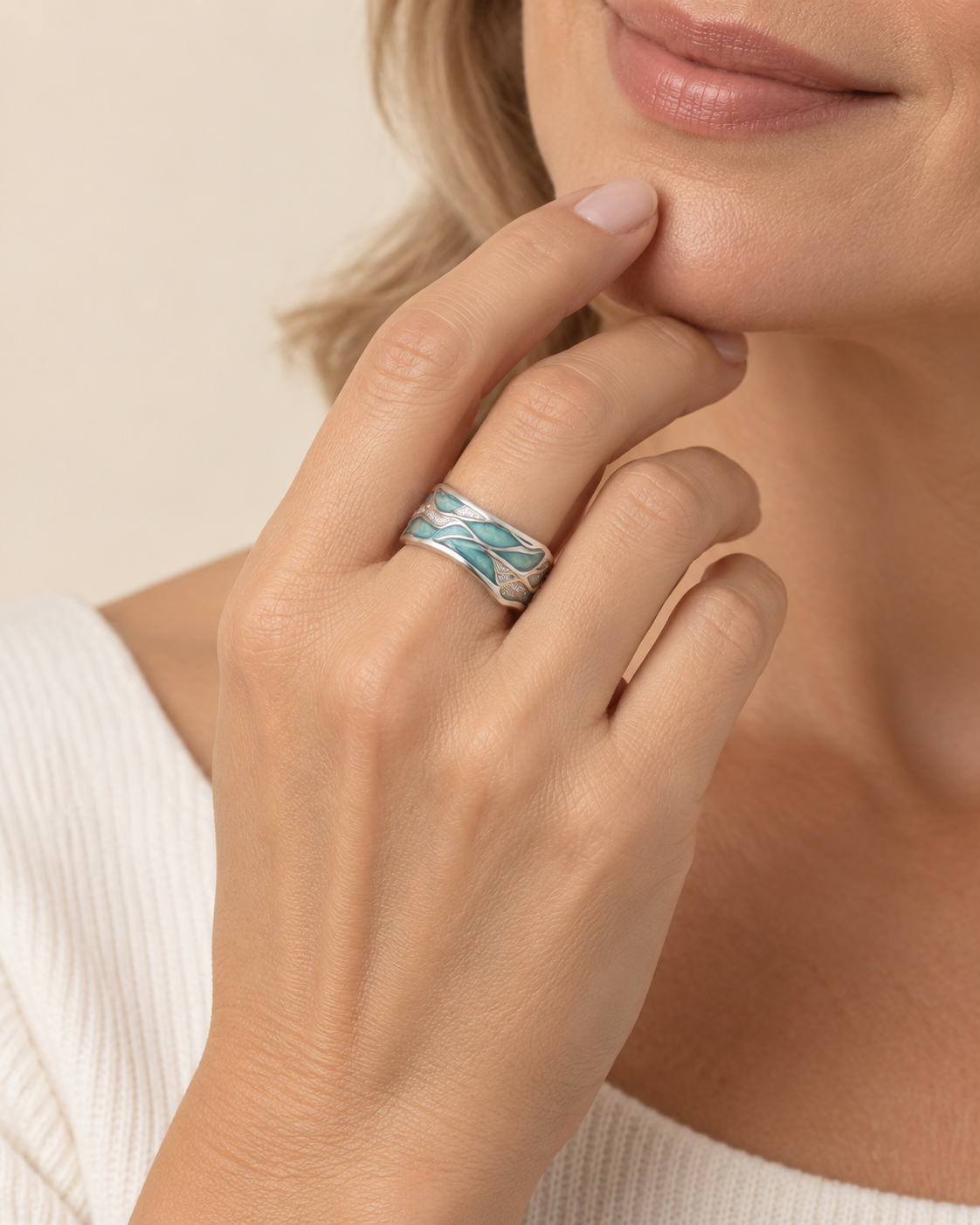 A close-up lifestyle shot of a woman wearing a silver band ring with a textured, layered turquoise and white pattern, resting on her index finger.