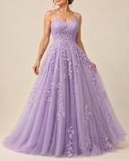 A woman wearing a lavender purple A-line formal gown with floral lace appliques and thin spaghetti straps, photographed against a solid beige studio background.