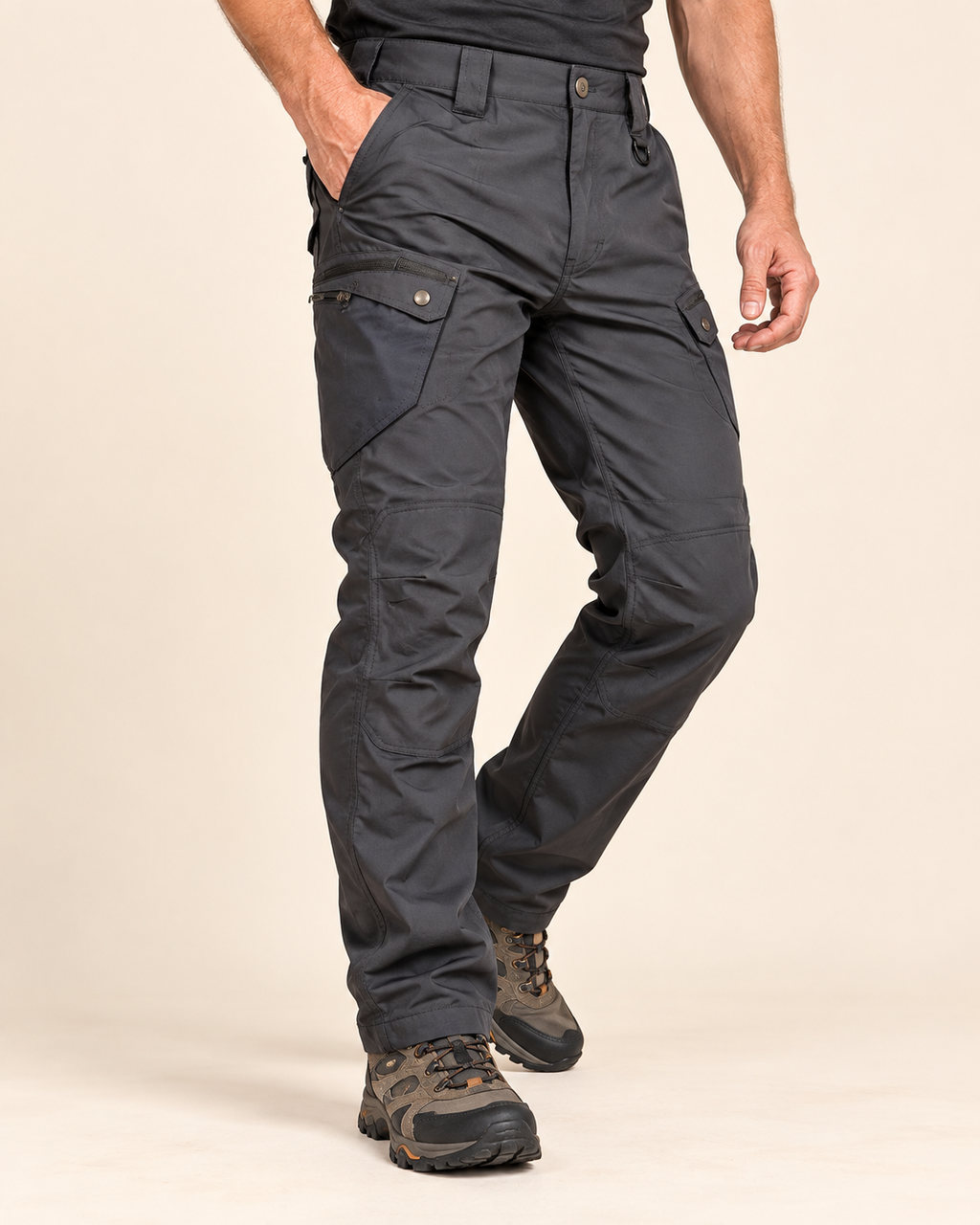 A person wearing dark charcoal cargo pants with brown hiking boots, shown from the waist down against a plain beige studio background.