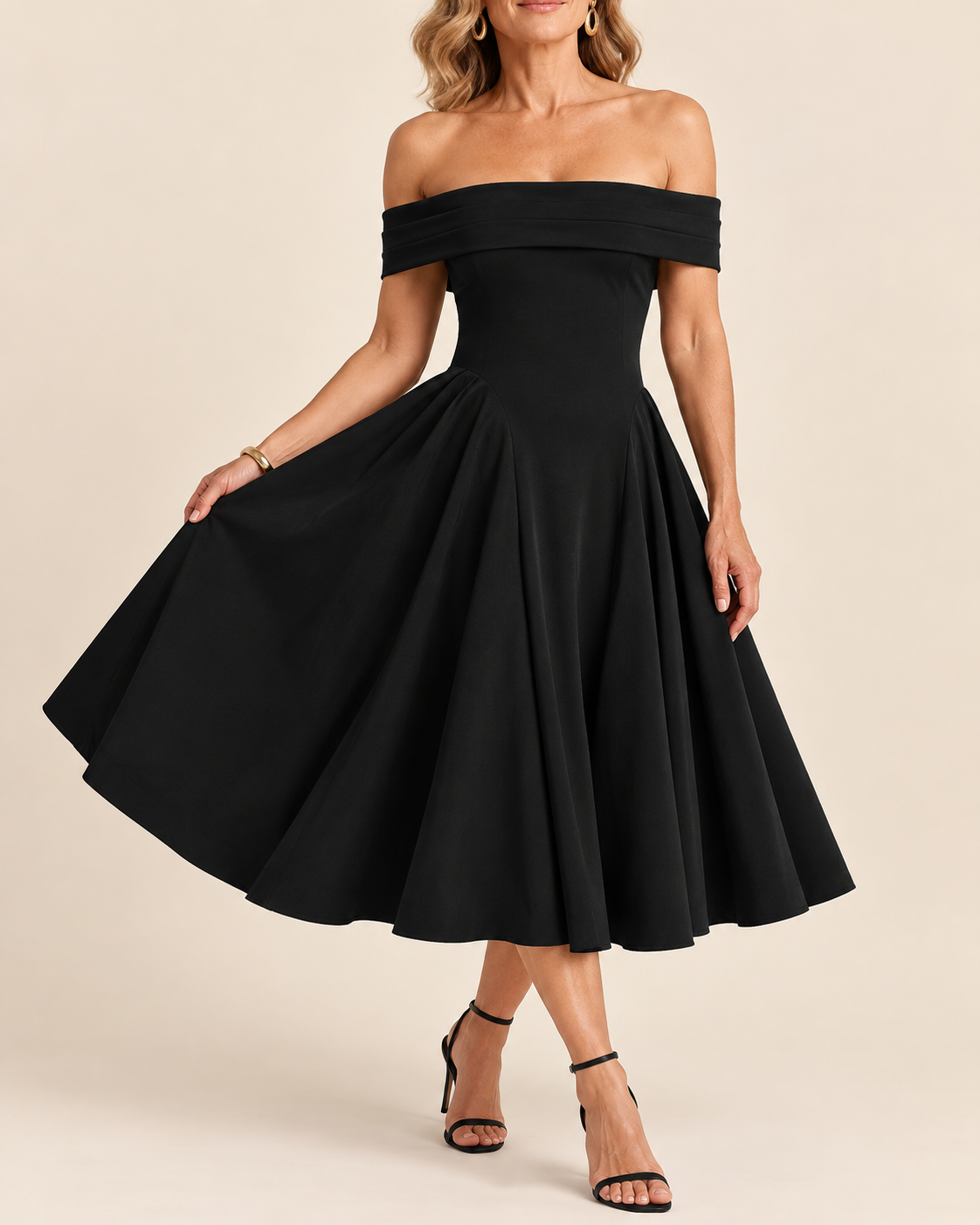A woman models an off-the-shoulder black midi dress with a flared skirt, paired with black strappy heels, against a solid beige studio background.