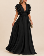A woman models a floor-length black gown with a plunging V-neckline, ruffled cap sleeves, and a gathered waist, photographed against a plain beige studio background.