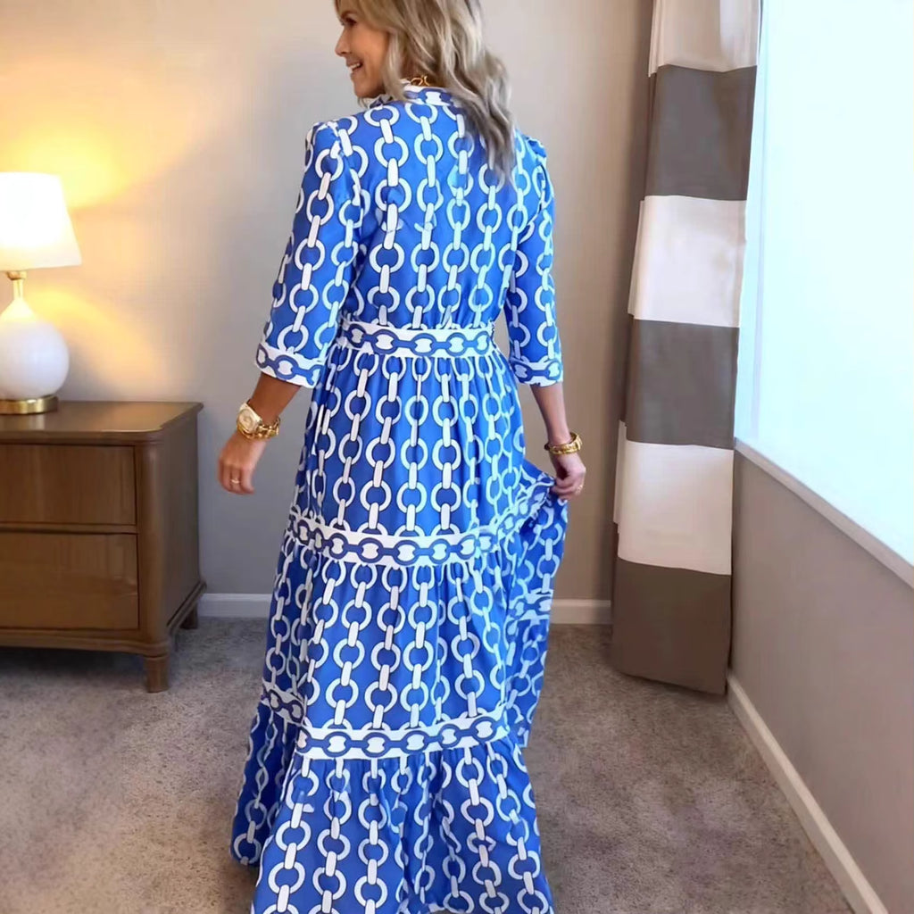 Woman wearing a blue and white patterned dress in a room with a lamp and striped curtain.