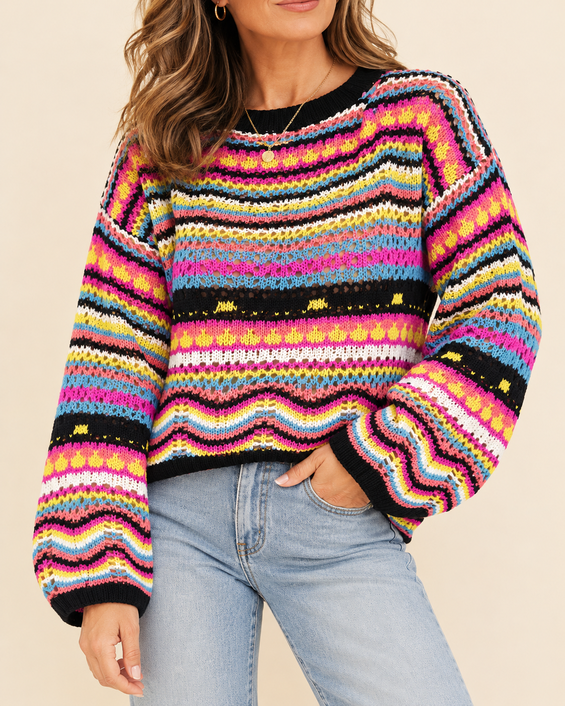 A woman wearing a vibrant, multicolored knit sweater with horizontal wavy stripes in pink, yellow, blue, orange, and black, paired with light-wash blue jeans against a solid beige background.